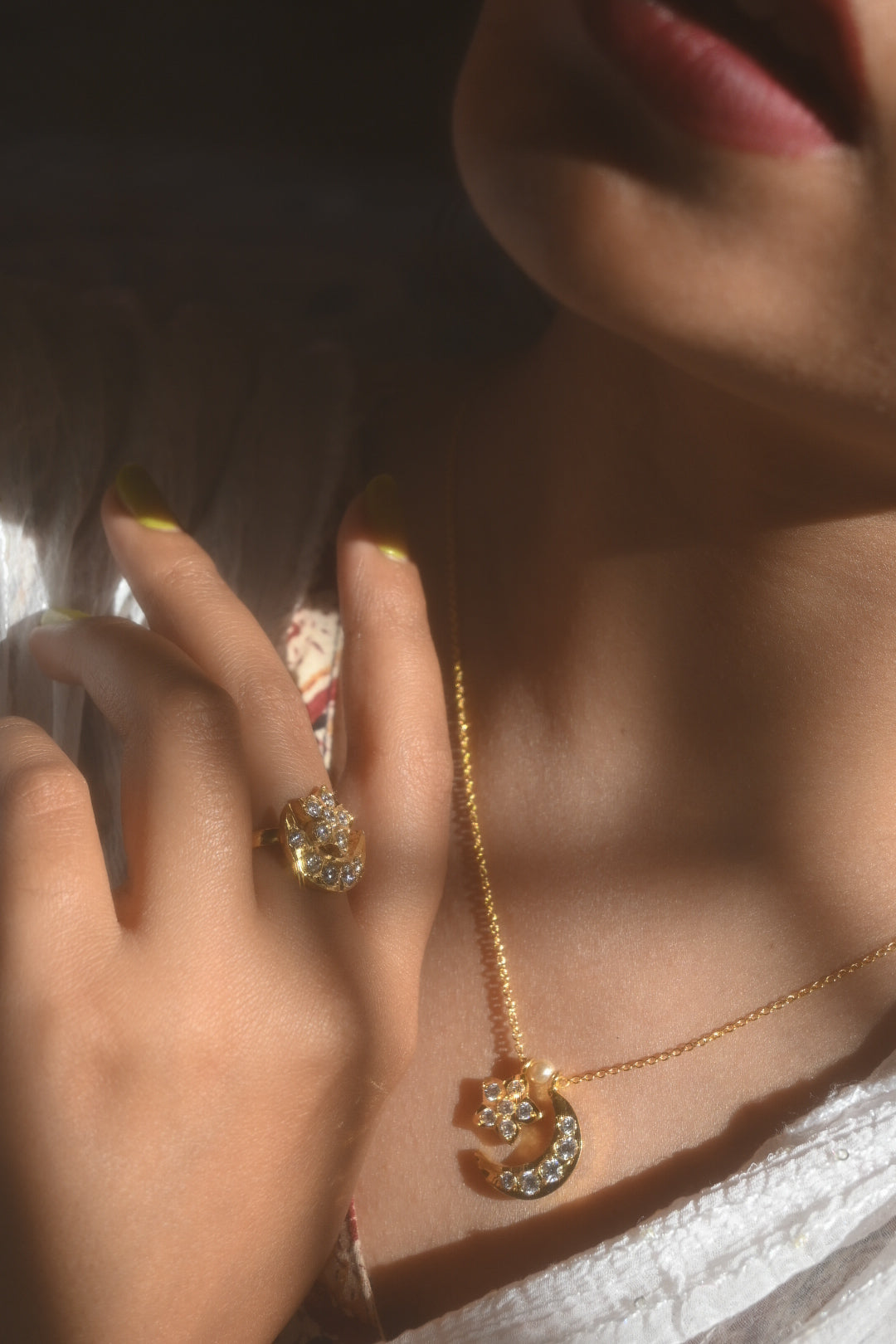 Close-up of a hand wearing a gold ring and gold necklace with a star pendant.