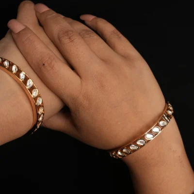 Sattva Gold Plated Bangles displayed on a traditional fabric background